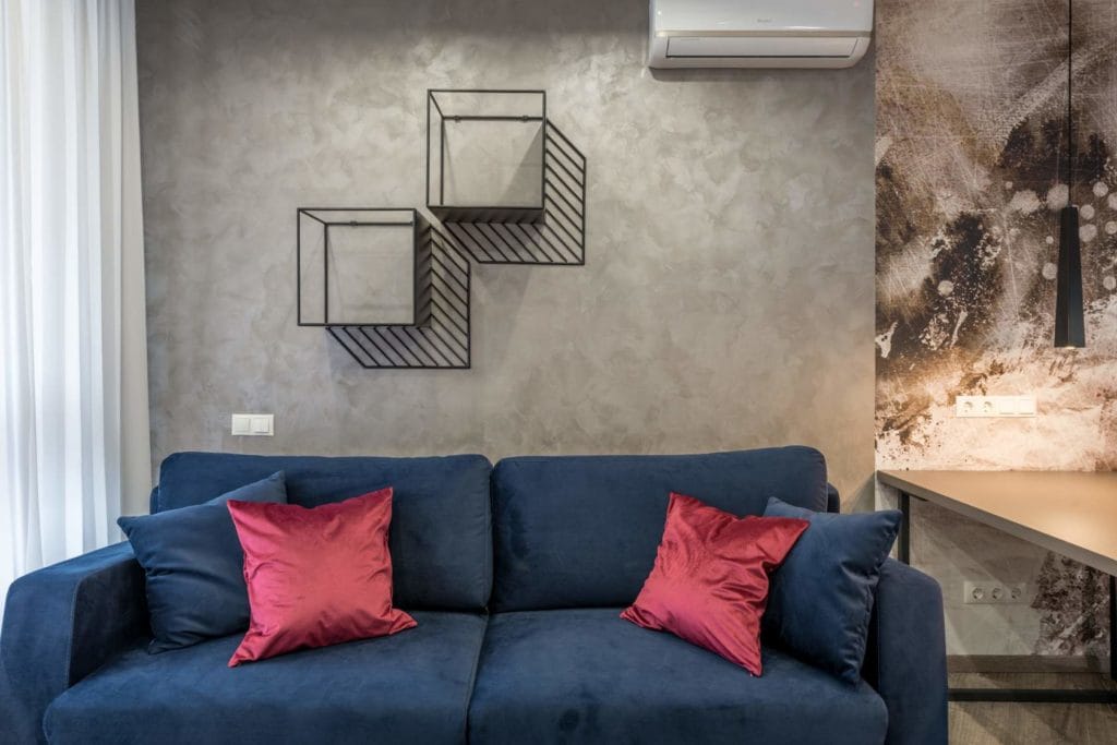 blå soffa med luftvärmepump på väggen bakom 