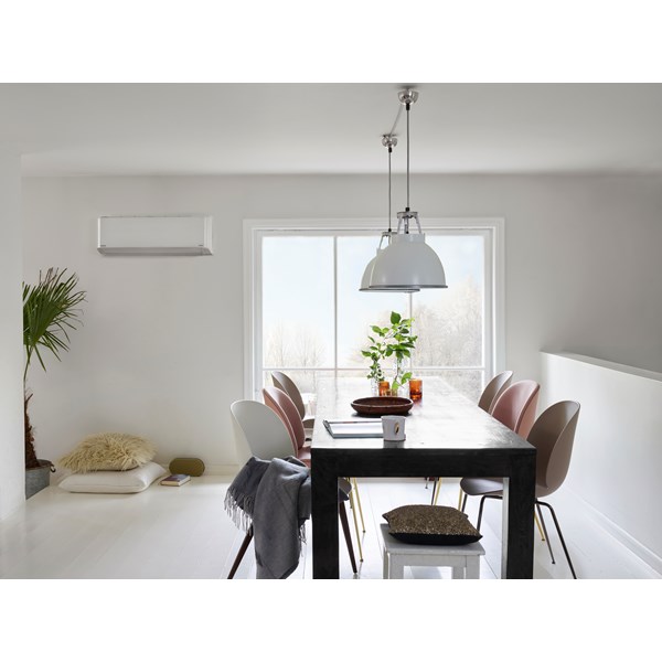 Bild på ett mörkt matbord med stolar. Två vita armaturer i taket och en rostfri luftvärmepump i bakgrunden.